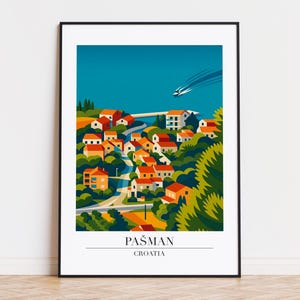Puede incluir: Una impresión artística enmarcada que presenta una ilustración estilizada de Pašman, Croacia. La obra de arte representa un pueblo costero con edificios de tejados naranjas, exuberante follaje verde y un cielo azul con un barco. El texto "PAŠMAN CROATIA" está en la parte inferior.