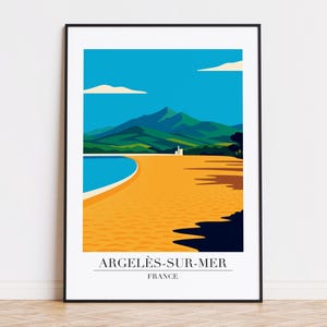Op de afbeelding: Een ingelijste kunstdruk met een gestileerd landschap van Argeles-sur-Mer, Frankrijk. De afbeelding toont een strand met goudkleurig zand, een turquoise zee en groene bergen onder een blauwe lucht met witte wolken. De tekst "ARGELÈS-SUR-MER FRANCE" staat onderaan.