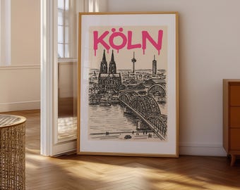May include: A framed art print featuring a black and white illustration of Cologne, Germany, with a bridge, cathedral, and skyline. The word "KÖLN" is in pink, dripping letters.