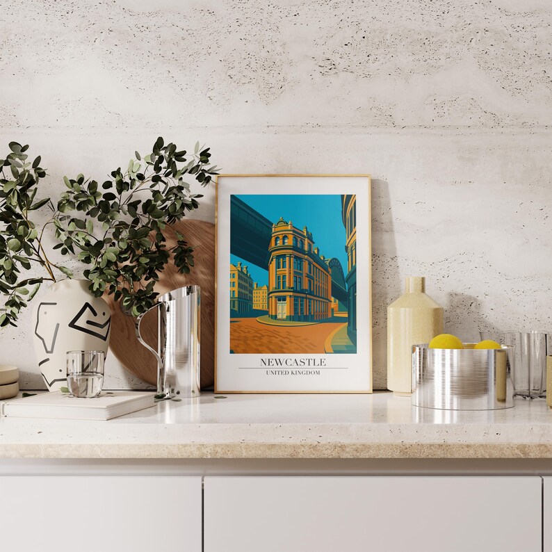 May include: A framed art print featuring a stylized illustration of a building in Newcastle, United Kingdom. The artwork showcases a vibrant color palette with a teal sky and orange and yellow buildings. The print is displayed on a white surface.