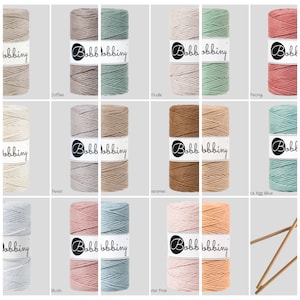 Può includere: Una collezione di 12 bobine di cordoncino di cotone in vari colori, tra cui caffè, nudo, peonia, perla, caramello, blush, azzurro e rosa chiaro. Ogni bobina è etichettata con il nome del marchio "Bobbiny".