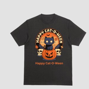 Puede incluir: Camiseta negra con un gráfico de un gato negro sentado en una calabaza de Halloween. El gráfico está rodeado de un círculo con el texto "Happy Cat-O-Ween". El texto "Happy Cat-O-Ween" también está impreso debajo del gráfico.