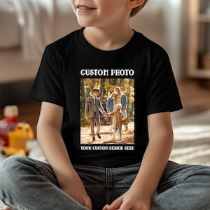 May include: Black t-shirt with a custom photo design. The photo shows a family walking in a forest. The text "CUSTOM PHOTO" is at the top, and "YOUR CUSTOM DESIGN HERE" is at the bottom. The shirt is worn by a child.