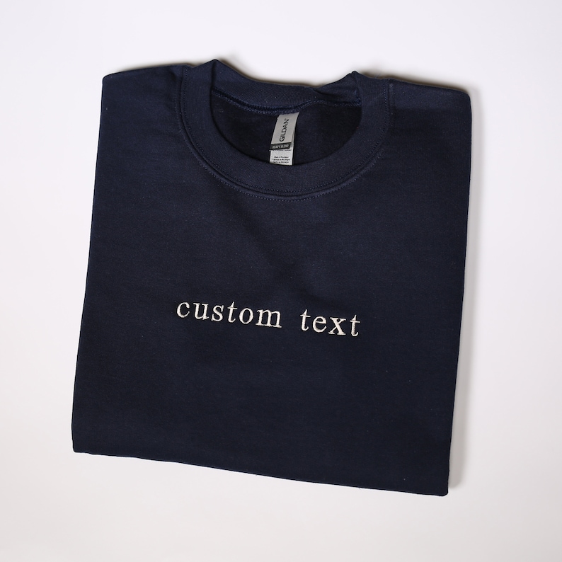 Może przedstawiać: Szarfa w kolorze granatowym z haftem "custom text" w kolorze białym z przodu.