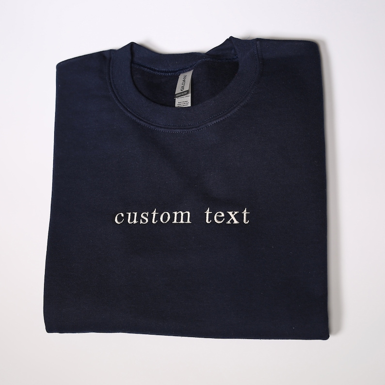 Może przedstawiać: Szarfa w kolorze granatowym z haftem "custom text" w kolorze białym z przodu.