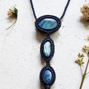 Puede incluir: Un collar de macram&eacute; negro con tres piedras de labradorita de forma ovalada. Las piedras son una mezcla de azul, verde y gris.