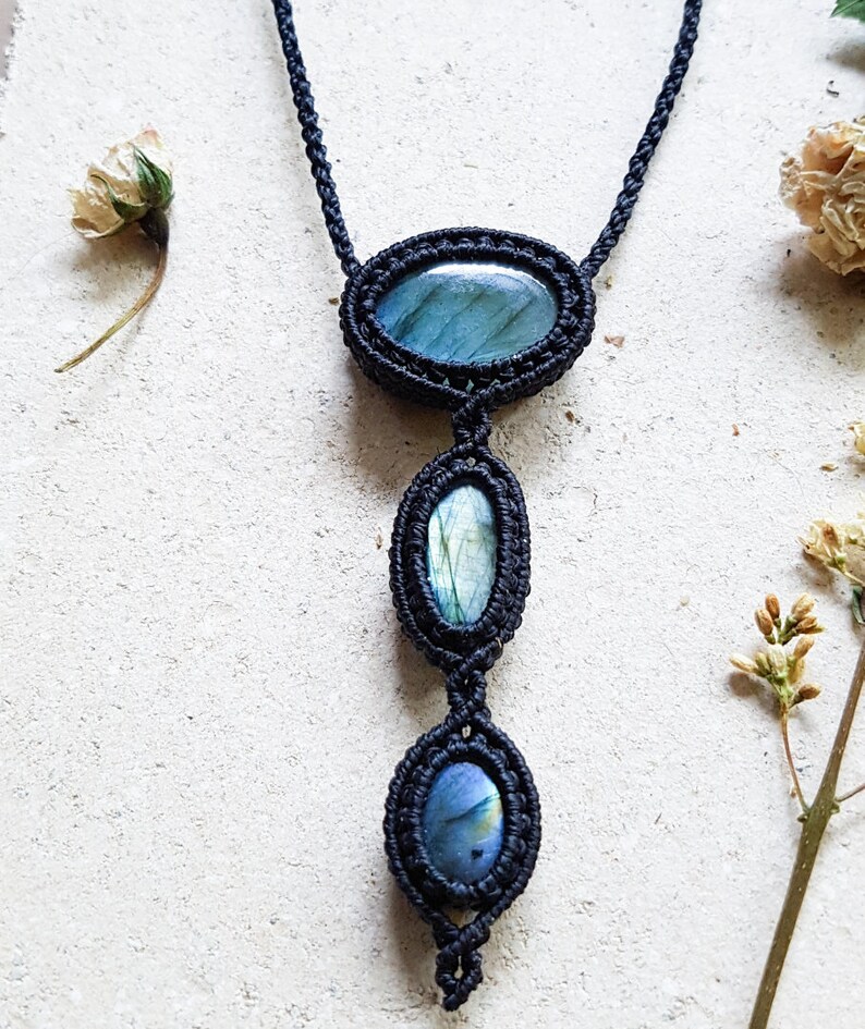 Puede incluir: Un collar de macram&eacute; negro con tres piedras de labradorita de forma ovalada. Las piedras son una mezcla de azul, verde y gris.