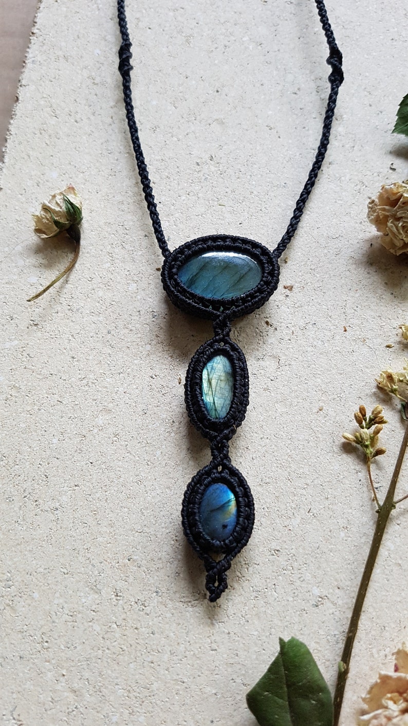 Puede incluir: Un collar de cord&oacute;n negro con tres piedras ovaladas de labradorita. Las piedras son de un azul profundo con destellos iridiscentes de verde y oro.