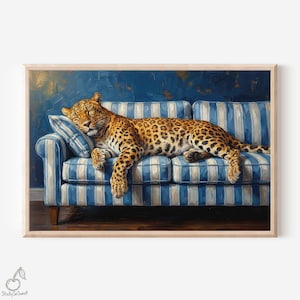 May include: A framed print featuring a leopard resting on a blue and white striped sofa. The leopard has a spotted coat and is lying on a striped pillow. The background is a dark blue wall.