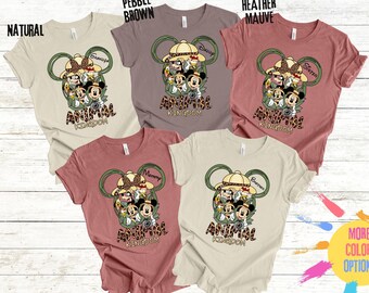 May include: Four t-shirts in different colors featuring a Mickey Mouse inspired design with the text "Animal Kingdom". The shirts are in the colors natural, pebble brown, heather mauve, and a darker shade of pink.