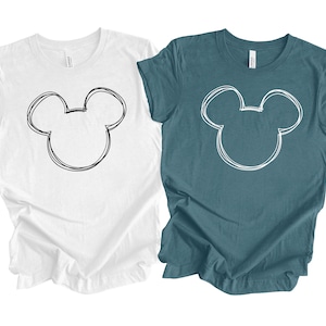 May include: Two t-shirts, one white and one teal blue, with a simple black and white outline of Mickey Mouse's head on the front.