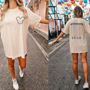 Pode incluir: Camiseta creme oversized com um contorno preto da cabe&ccedil;a do Mickey Mouse na frente. A parte de tr&aacute;s da camisa tem um jogo de palavras com o texto "TO ANYONE BEHIND ME, WE'RE IN THE LINE TOGETHER, ENJOY".