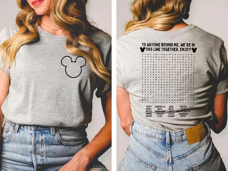 Pode incluir: Uma camiseta cinza com um contorno preto do Mickey Mouse na frente e uma busca de palavras nas costas. A parte de tr&aacute;s da camisa tem o texto "TO ANYONE BEHIND ME, WE'RE IN THIS LINE TOGETHER. ENJOY!"