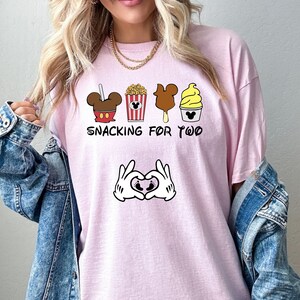 May include: Pink t-shirt with a graphic of Mickey Mouse snacks and the text "Snacking for Two" with Mickey Mouse hands making a heart shape with a baby footprint inside.