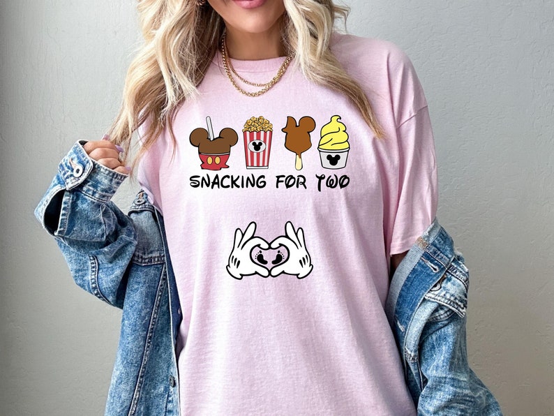 May include: Pink t-shirt with a graphic of Mickey Mouse snacks and the text "Snacking for Two" with Mickey Mouse hands making a heart shape with a baby footprint inside.