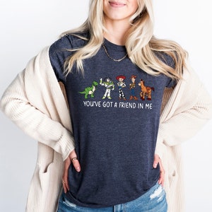 May include: A dark heather grey t-shirt with a graphic of characters from the Toy Story movie franchise. The text "You've got a friend in me" is printed below the graphic.
