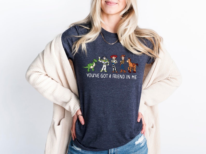 May include: A dark heather grey t-shirt with a graphic of characters from the Toy Story movie franchise. The text "You've got a friend in me" is printed below the graphic.