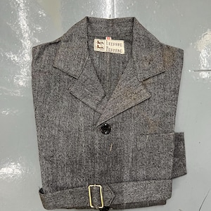 May include: A gray tweed blazer with a notched lapel, a single black button, and a matching belt with a gold-colored buckle. The label reads "LEOPARD NORMAND".