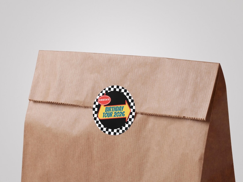May include: A brown paper bag with a circular sticker. The sticker has a black background with a checkered border. The sticker text reads "Birthday Tour 2026" with an arrow design.