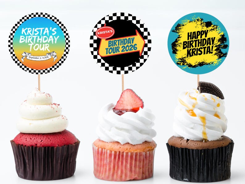 May include: Three cupcakes with decorative toppers. The toppers have text that reads "Krista's Birthday Tour" and "Happy Birthday Krista!" The cupcakes have white frosting and are decorated with a strawberry, an Oreo cookie, and red sprinkles.