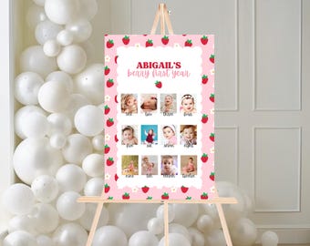Op de afbeelding: Een roze poster op een houten ezel, met een aardbeienthema. De poster heeft de tekst "ABIGAIL'S berry first year" en een geschulpte rand. Het bevat twaalf babyfoto's, elk gelabeld met een maand.