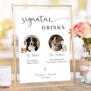May include: A framed sign with the words "signature DRINKS" in elegant script. The sign features two drink options, "The Pluto" and "The Sampson", each with a photo of a pet and a list of ingredients. The sign is personalized with a couple's names and a date.