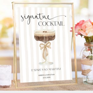 Op de afbeelding: Een decoratief bord met de tekst "signature COCKTAIL" en "ESPRESSO MARTINI". Het bord heeft een aquarel illustratie van de cocktail en is versierd met een strik. Een vaas met bloemen en een kandelaar zijn ook in de afbeelding aanwezig.