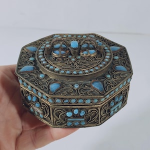Peut inclure: Boîte à bijoux octogonale avec un design filigrané complexe et des accents turquoise.