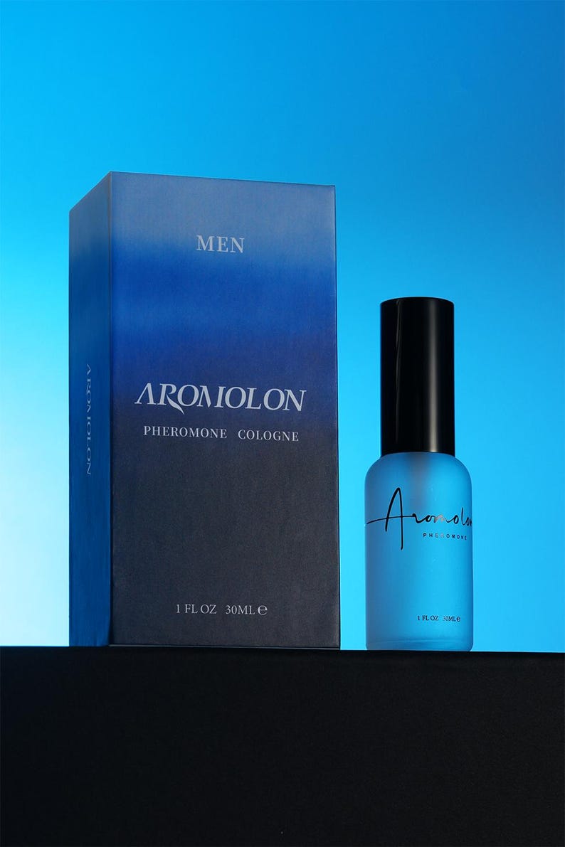 Puede incluir: Una caja degradada azul y un frasco de colonia de vidrio esmerilado con tapa negra. La caja dice "MEN" y "AROMIOLON PHEROMONE COLOGNE". El frasco tiene el nombre de la marca y "PHEROMONE" impreso. El frasco es de 30 ml.