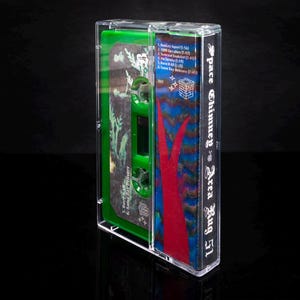 May include: A clear plastic cassette tape case with a green and red design. The case has the text "Space Chimney Area Rug 51" printed on the side. The cassette tape is not visible.