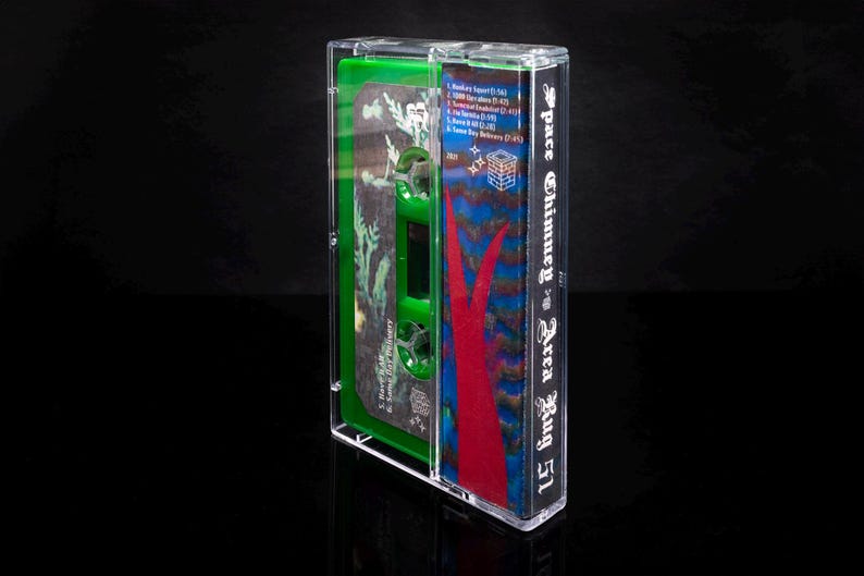 May include: A clear plastic cassette tape case with a green and red design. The case has the text "Space Chimney Area Rug 51" printed on the side. The cassette tape is not visible.