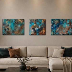 Puede incluir: Tres pinturas abstractas con tonos turquesa, marrón y dorado cuelgan sobre un sofá seccional beige. La obra de arte presenta superficies texturizadas y marcos oscuros, creando una estética moderna. Las pinturas añaden un toque de color a la sala de estar neutral.