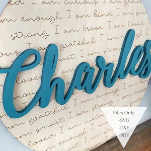 May include: A teal blue wooden name sign with the name "Charles" in a cursive font. The sign is on a wooden background with a handwritten inscription that reads "I am curious. I am grateful. I am smart. I am enough. I am kind. I am strong. I am brave. I am loved. I am..."