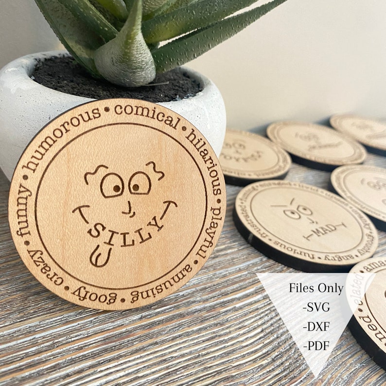 May include: A wooden coaster with a cartoon face and the word "Silly" written underneath. The coaster is surrounded by a circle of text that reads "goofy, crazy, funny, humorous, amusing, playful, hilarious, comical".