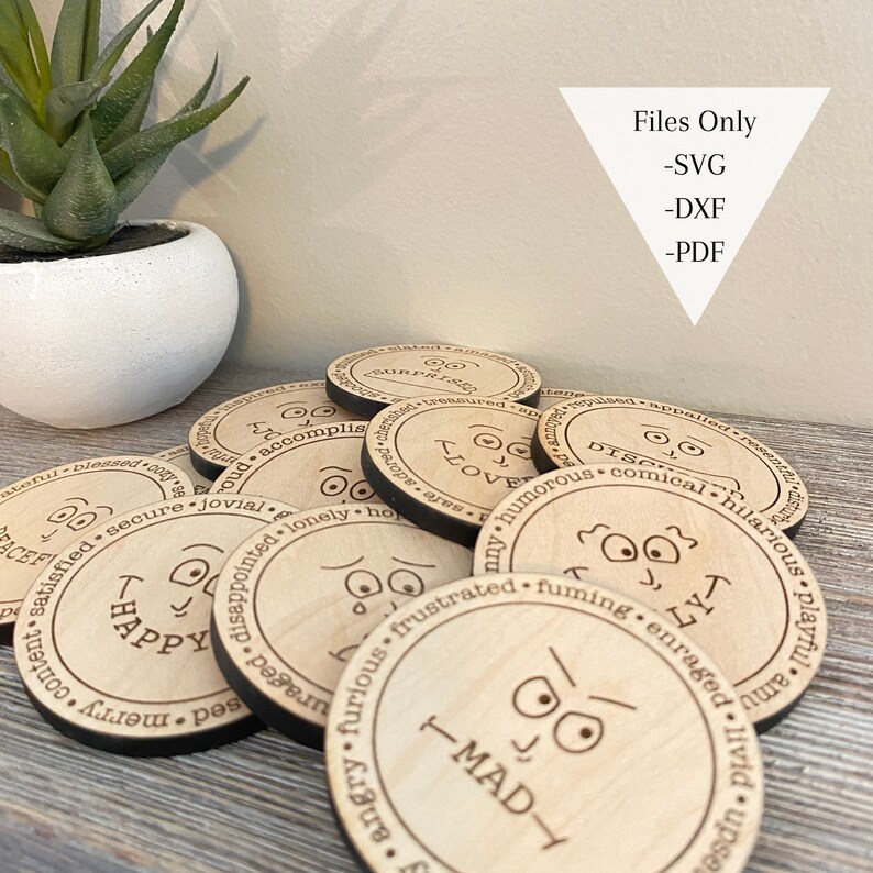 May include: A set of wooden circles with different facial expressions and words like "Happy", "Love", "Mad", and "Disappointed". The circles are arranged in a pile on a wooden surface. The text "Files Only - SVG - DXF - PDF" is visible in the top right corner of the image.