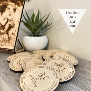 May include: A set of wooden coasters with different facial expressions and words like "Happy", "Mad", "Silly", and "Furious". The coasters are arranged in a circle on a wooden surface. The text "Files Only - SVG - DXF - PDF" is visible in the upper right corner of the image.