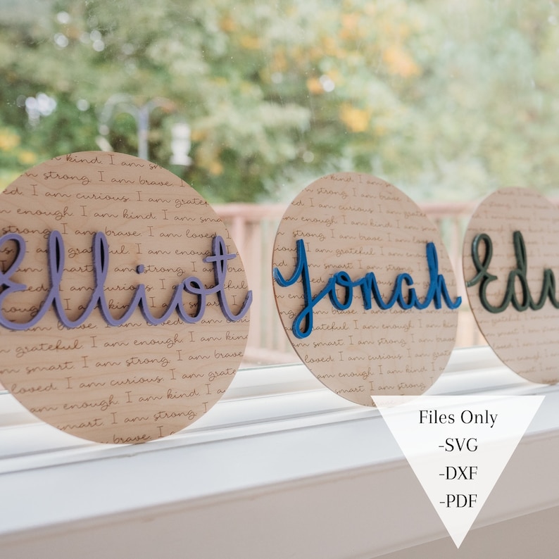 May include: Three round wooden signs with the names "Elliot", "Jonah", and "Eden" written in colorful script. The signs are decorated with a background of brown paper with a repeating pattern of text.