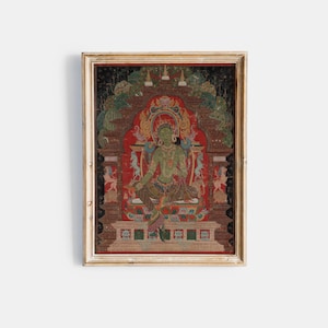 May include: A framed, vintage-style painting featuring a seated green figure with a halo, set against a red backdrop. The artwork has intricate details, including ornate architectural elements and decorative figures. The frame is a warm gold colour.