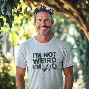 Peut inclure: Un t-shirt gris avec le texte "I'm not weird I'm limited edition" imprimé sur le devant.