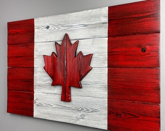 May include: A wooden Canadian flag with a red maple leaf in the center. The flag is made of reclaimed wood and has a distressed white and red paint finish.