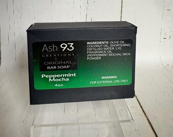 May include: A rectangular black box of Ash 93 Creations Peppermint Mocha bar soap. The label features green accents, lists ingredients including olive oil and coconut oil, and states a weight of 4 oz. A warning for external use is printed.