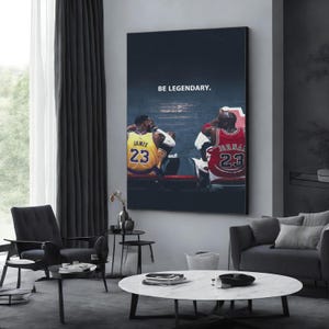 May include: A large wall art print featuring basketball legends LeBron James and Michael Jordan, both wearing the number 23. The text "BE LEGENDARY" is printed at the top. The artwork is displayed in a modern living room setting.