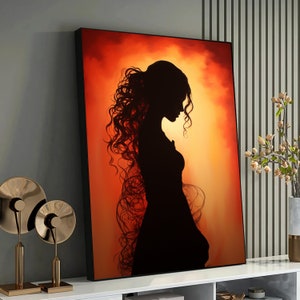 May include: A silhouette of a woman with long, flowing hair against a warm orange and yellow background. The woman is wearing a long dress and is looking down.