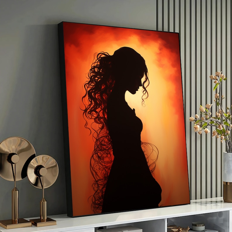 May include: A silhouette of a woman with long, flowing hair against a warm orange and yellow background. The woman is wearing a long dress and is looking down.