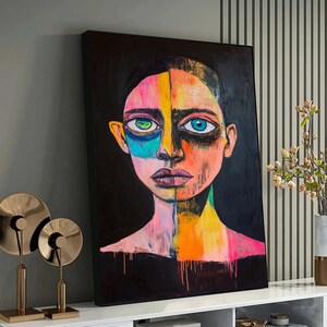 Könnte beinhalten: Abstrakte Porträtmalerei einer Person mit einem farbenfrohen Gesicht. Das Gesicht ist in Abschnitte in Pink, Gelb, Orange, Blau und Grün unterteilt. Der Hintergrund ist schwarz.