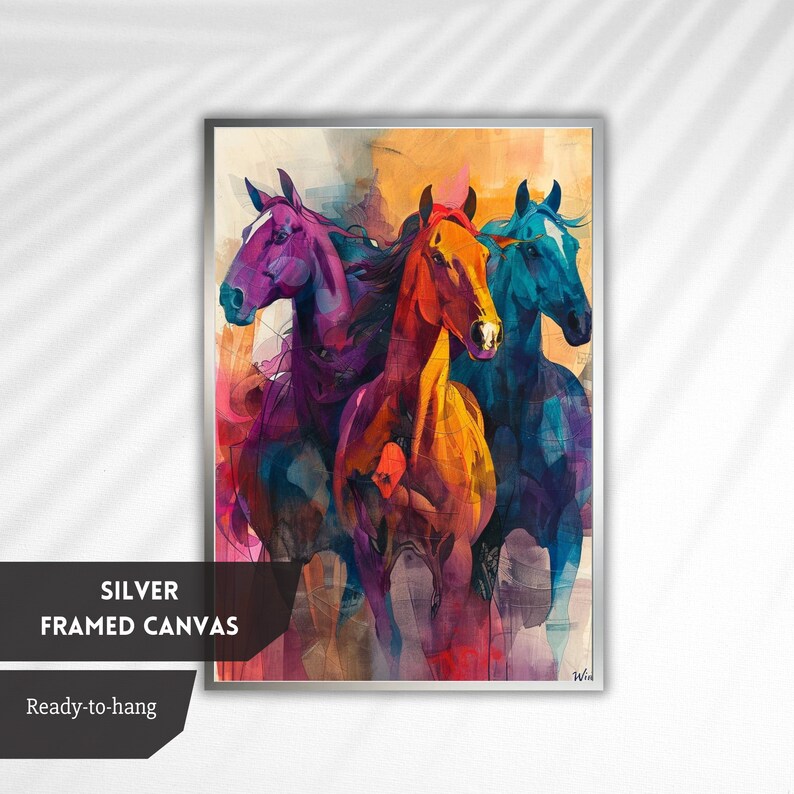 May include: A silver framed canvas print featuring an abstract painting of three horses running. The horses are painted in shades of purple, orange, and blue, with a watercolour-like effect. The background is a muted yellow and orange.