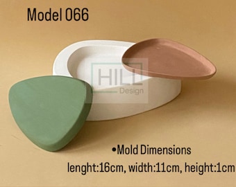 May include: A set of three modern, minimalist decorative pieces. Includes a white oval-shaped container, a triangular green piece, and a teardrop-shaped terracotta plate. The text "Model 066" and "HILL Design" are visible. The mold dimensions are 16cm long, 11cm wide, and 1cm high.