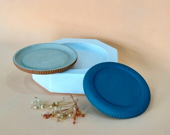 May include: A white octagonal tray with a light blue rim and a smaller light blue tray with a brown rim. A teal blue round tray with a raised rim is also included.