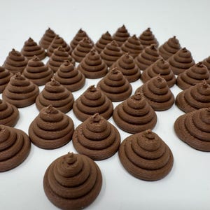 May include: A collection of 30 small, brown, ceramic poop-shaped figurines. The figurines are arranged in rows on a white surface.