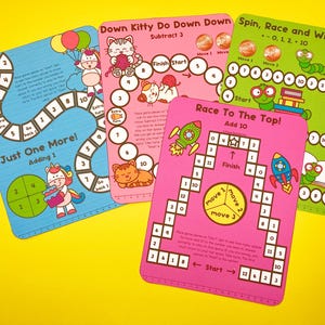 Puede incluir: Cuatro tableros de juego coloridos con diferentes temas e instrucciones. Los tableros presentan un unicornio, un gato, un cohete y un gusano. Los juegos est&aacute;n dise&ntilde;ados para que los ni&ntilde;os aprendan habilidades matem&aacute;ticas como sumar, restar y contar.